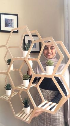 a woman is holding up a shelf made out of hexagonal shelvings