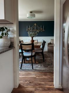 a dining room table with chairs and a vase filled with flowers on top of it