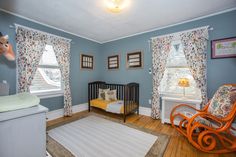 a baby's room with blue walls and floral curtains