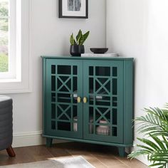 a green cabinet sitting in the corner of a room next to a potted plant