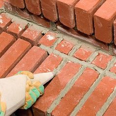 a brick laying on top of a sidewalk next to a person with gloves and mittens