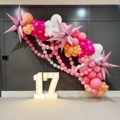 the balloon arch is decorated with pink, white and orange balloons that spell out 17