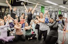 a group of people in a gym doing exercises with their hands up and arms raised