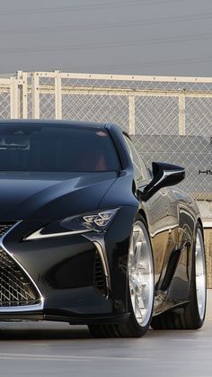 a black sports car parked in front of a fence