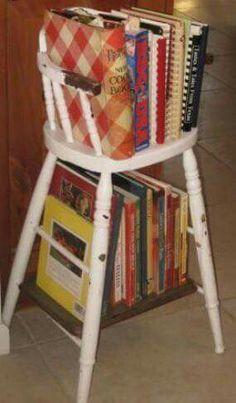 a stack of books sitting on top of a white chair next to a book shelf