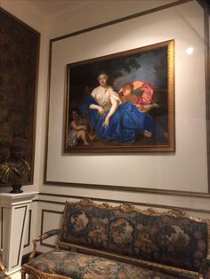 a painting hanging on the wall next to a couch in a room with ornate furniture