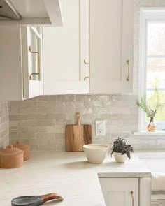 a white kitchen with marble counter tops and wooden utensils on the countertop