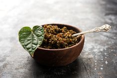 a wooden bowl filled with dried herbs and a green leaf in the center - stock photo - images