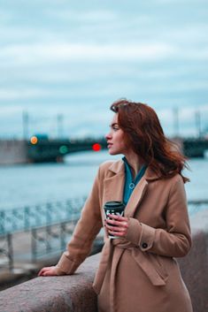 a woman in a coat is holding a coffee cup