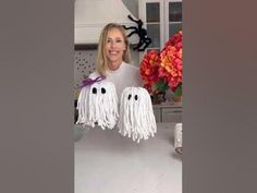 a woman holding up two fake ghost decorations