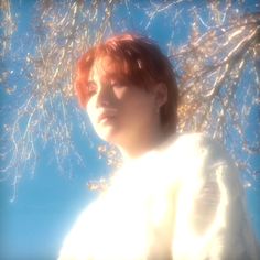 a woman with red hair standing under a tree