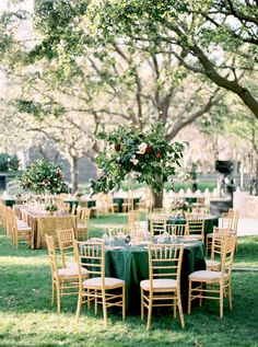 an outdoor wedding reception setup with green tablecloths and gold chairs