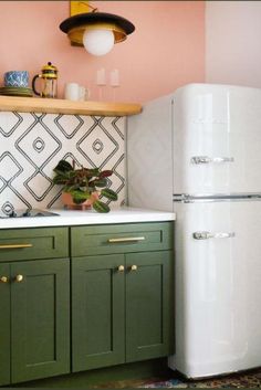 a white refrigerator freezer sitting inside of a kitchen next to green cabinets and drawers