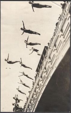 black and white photograph of people diving off the side of a building