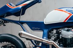 a blue and white motorcycle parked in front of a wall with an orange stripe on it