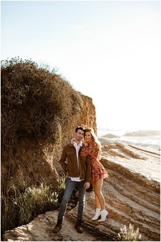 a man and woman standing next to each other near the ocean