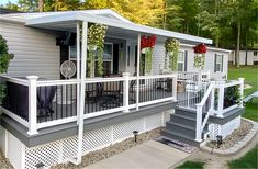 a mobile home with white railings and flowers on the porch