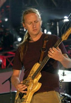 a man with long hair playing an electric guitar