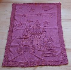 a pink towel with a castle on it sitting on top of a wooden floor next to a wall