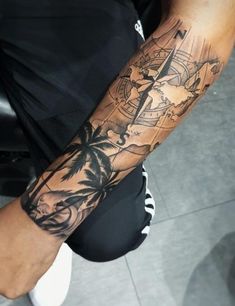 a man's arm with a compass and palm tree tattoo on the left forearm