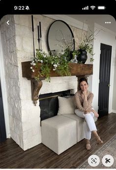 a woman sitting on a couch in front of a fireplace