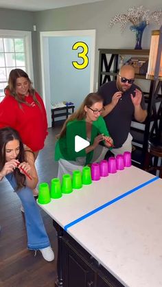 a group of people standing around a table with cups on it and numbers in the middle