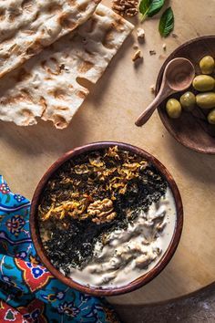 an assortment of food on a table including pita bread, hummus and olives