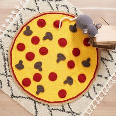 a small mouse is sitting on top of a pizza rug with red and black dots