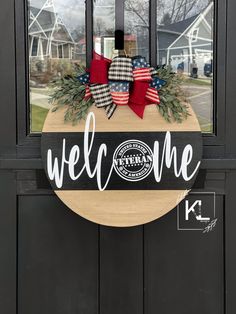 a welcome sign hanging on the front door of a house with red, white and blue decorations