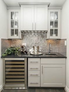 a kitchen with white cabinets and black counter tops in the center is a wine rack