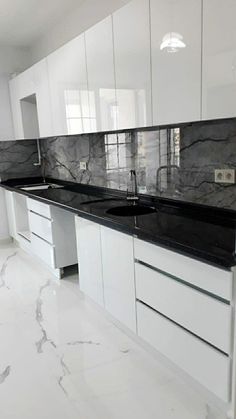 an empty kitchen with marble counter tops and white cupboards on either side of the sink