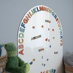 a stuffed animal sitting next to a white board with letters on it