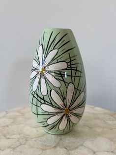 a green vase with white flowers painted on it