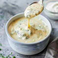 a spoon full of cheese sauce being lifted from a bowl