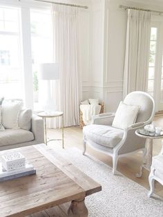 a living room filled with white furniture and lots of window curtains on the windowsill