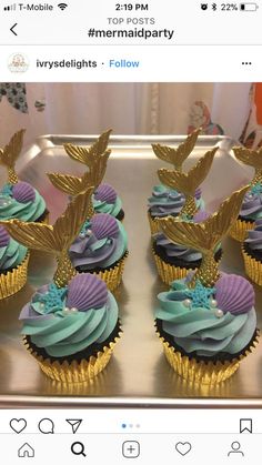 cupcakes with blue and purple frosting are on a metal tray next to other cupcakes