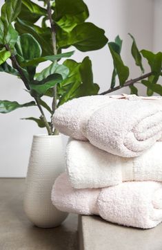 a stack of white towels next to a potted plant