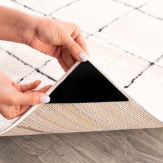 a woman is placing an area rug on the floor with her hand and touching it