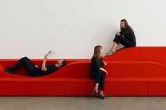 two women are sitting on a red couch