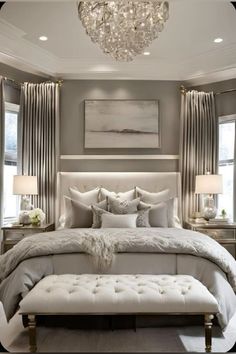 a large bed sitting under a chandelier in a bedroom next to two windows