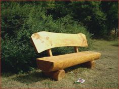 a wooden bench sitting in the middle of a field next to some bushes and trees