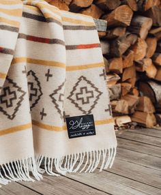 two blankets are sitting next to each other on a wooden floor with logs in the background