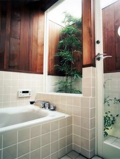 a bathroom with a bamboo tree in the window and white tiles on the floor,