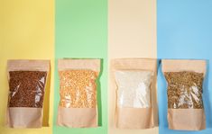 three bags of cereal are lined up against a multi - colored wall and one bag is empty