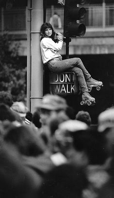 a woman sitting on top of a traffic light next to a sign that says don't walk