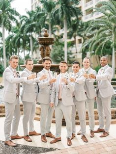 a group of men standing next to each other in front of a fountain holding glasses