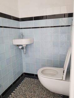 a white toilet sitting in a bathroom next to a wall mounted faucet and sink