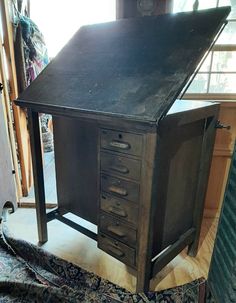 an old wooden desk with drawers and a rug on the floor in front of it