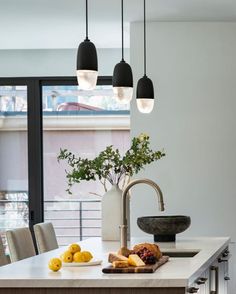 a kitchen with an island, sink and hanging lights