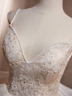 the back of a wedding dress with beading and pearls on it's skirt